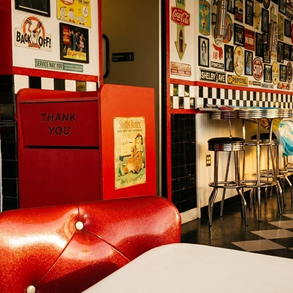 Retro diner interior with red booths, black and white checkered floor, and vintage wall decor.
