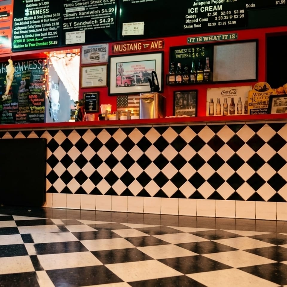 A retro diner interior with a black and white checkered floor and counter, red walls, and menu boards.